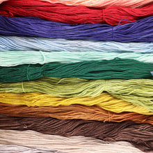 Load image into Gallery viewer, skeins of hand-dyed merino yarn in twelve semi-solid colours laid side by side
